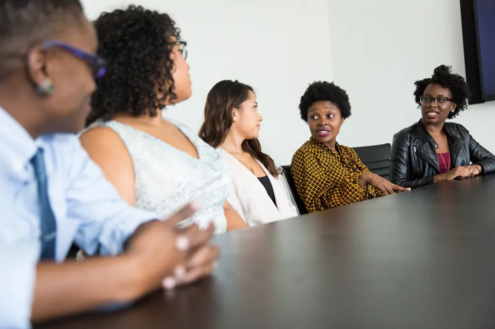 Illustrative photograph of colleagues in discussion around a boardroom table, representing corporate and commercial legal work.